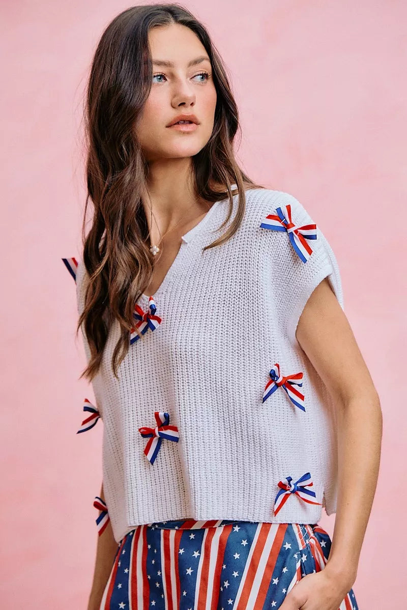 Off-white knit dolman sweater top with colorful ribbon bow details on the front