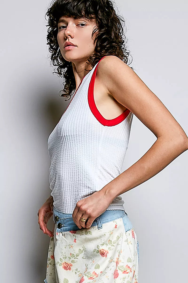 Off-white ribbed sleeveless tank with red contrast V-neck trim and armholes