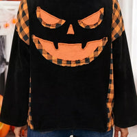 Black long-sleeve top back view featuring orange plaid pumpkin face applique