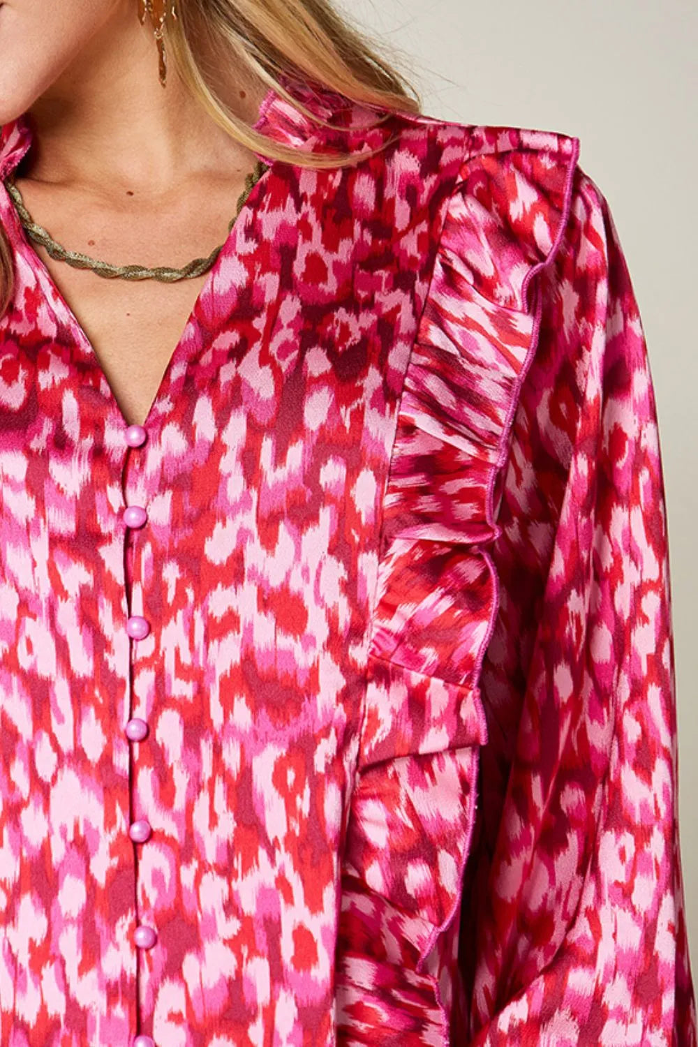 Hot pink printed blouse close-up showing button placket and ruffled shoulder trim