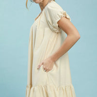Cream shift mini dress with short puff sleeves and gathered ruffle hem detail.