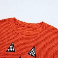 Orange sweater front with jack-o'-lantern face and black-and-white triangle details