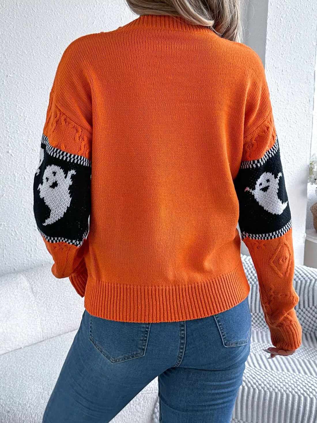 Orange sweater back view with black-and-white ghost stripe on the sleeves