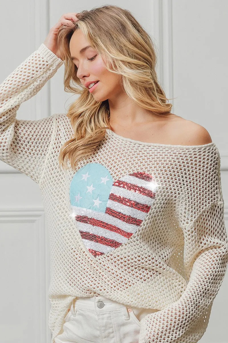 Off-white sequin knit sweater with American flag heart design, wide neckline.