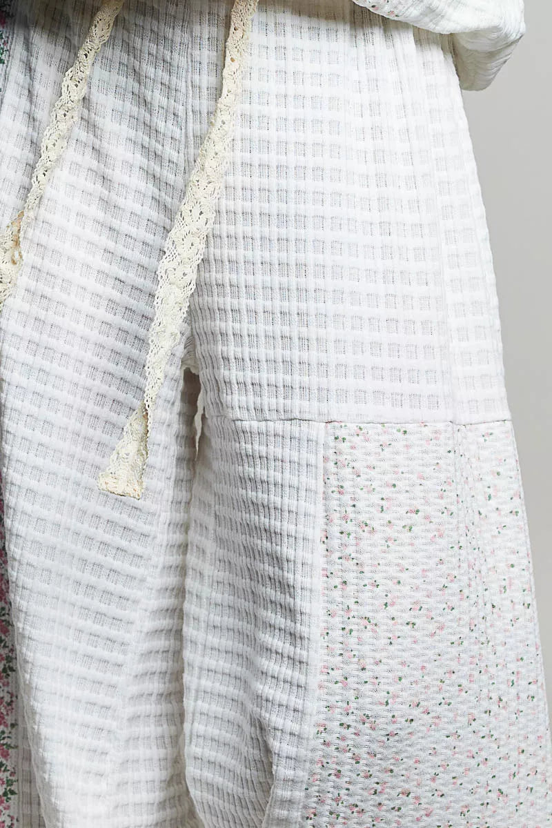 Ivory patchwork knit pants close-up: textured fabric panels and speckled side panel