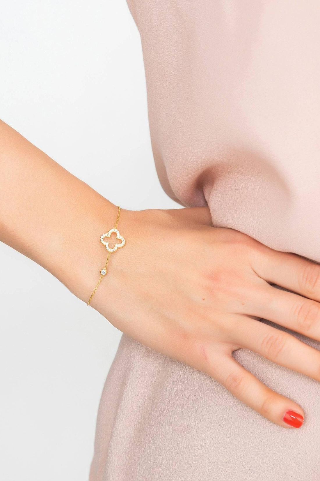 Gold open clover charm bracelet on wrist with adjustable chain