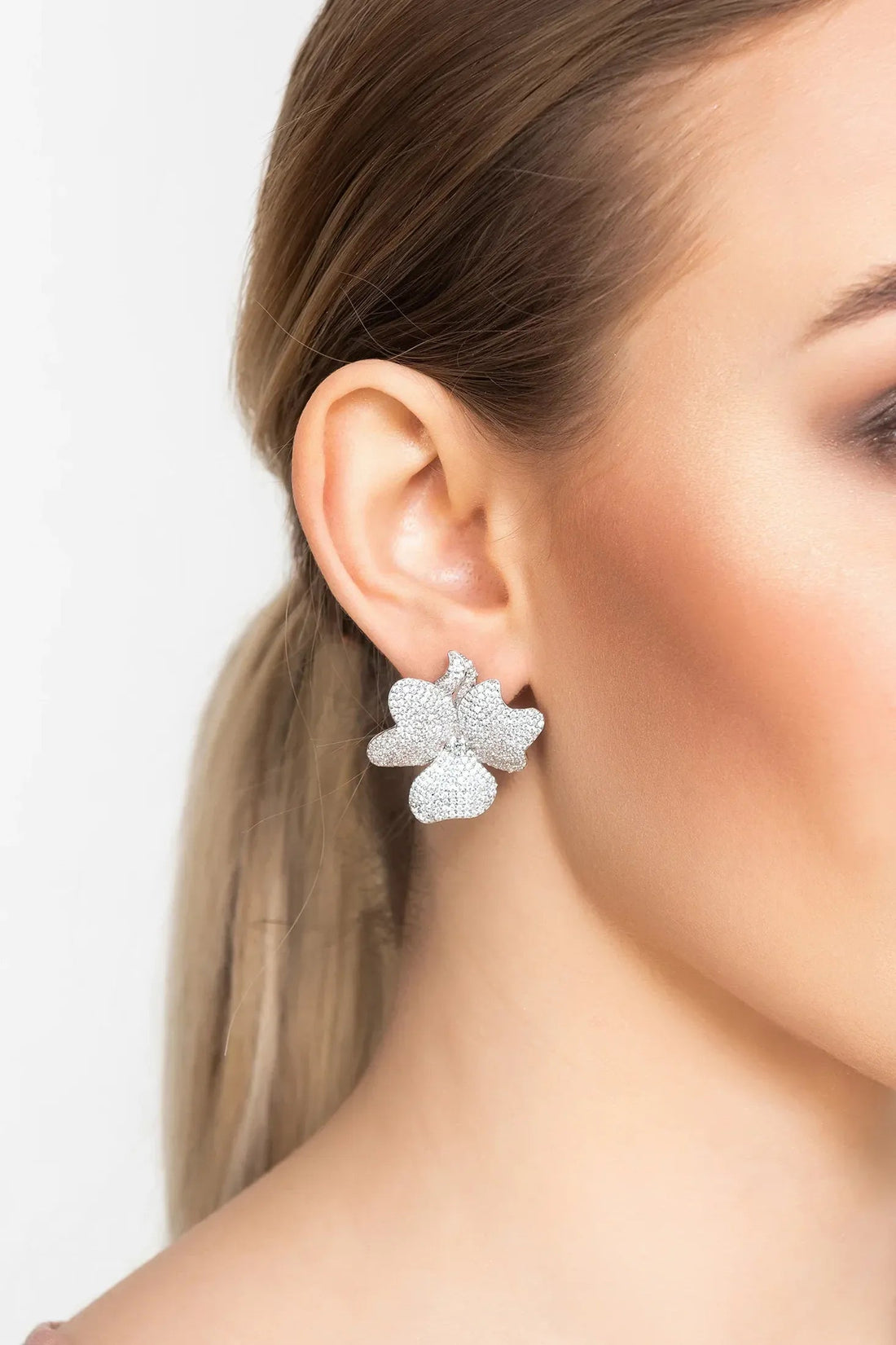 Silver-tone textured flower clip-on stud earrings on ear for a bold bloom look