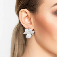 Silver-tone textured flower clip-on stud earrings on ear for a bold bloom look