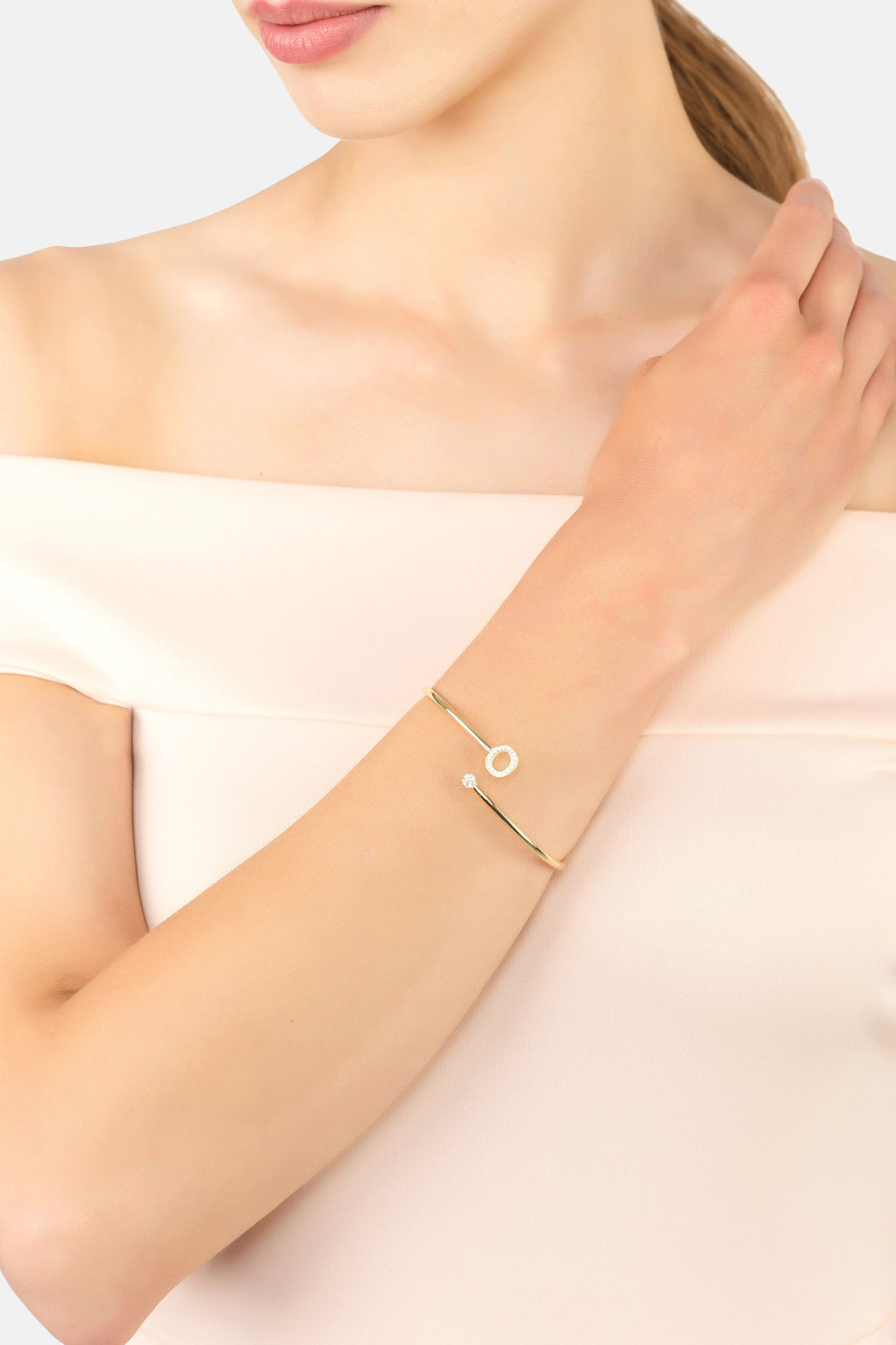Silver initial O bangle on wrist with round charm and tiny stone