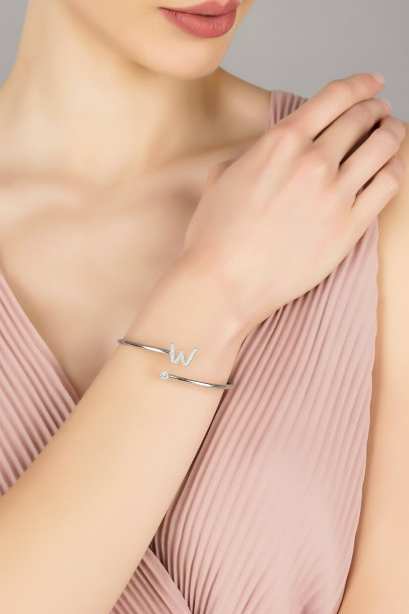 Silver initial W bangle on wrist with slim cuff and small stone accents