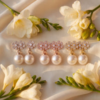 Rose-gold tone floral crystal and pearl drop earrings, laid flat