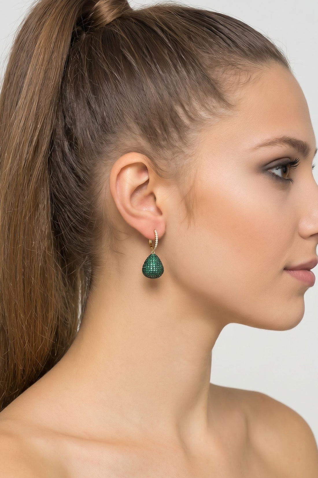 Emerald-green teardrop gemstone drop earring on gold hook, close side view
