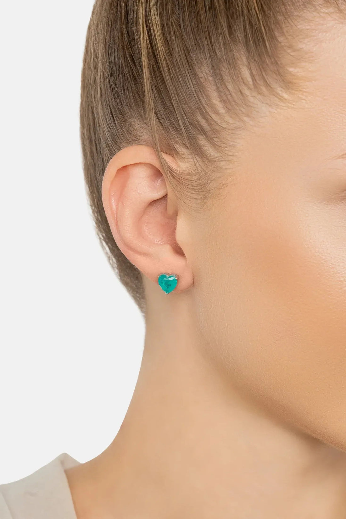 Turquoise heart stud earrings on ear with silver backs