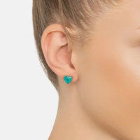 Turquoise heart stud earrings on ear with silver backs