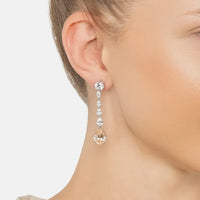 Silver drop earrings with small round stones and one champagne pear-shaped stone, on ear