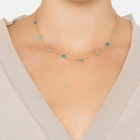 Gold-tone blue-stone necklace worn at the collarbone on a model