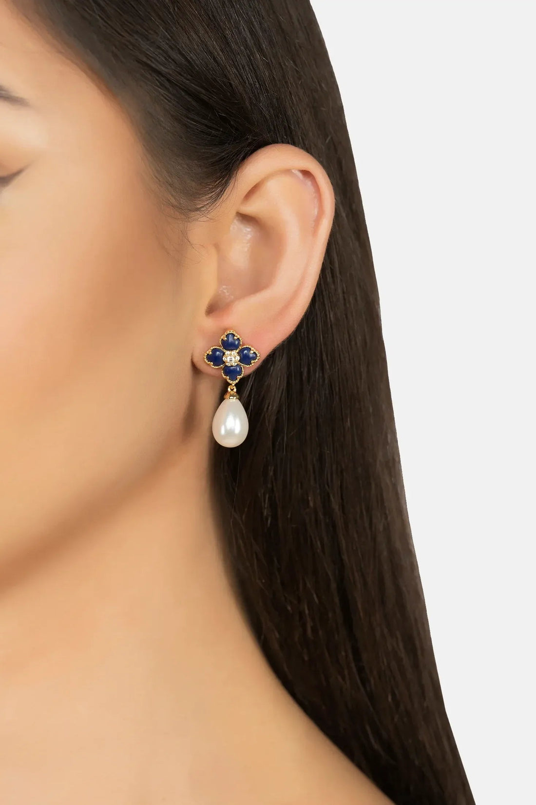 Gold-tone navy clover earrings with crystal detail and white pearl drops on ear