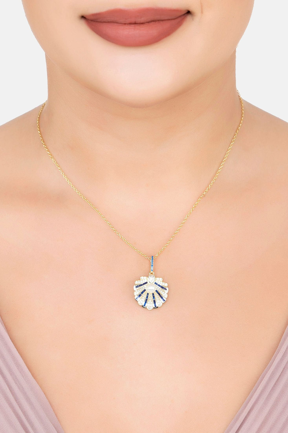 Gold necklace on model with small blue scallop-shell pendant and pearl center