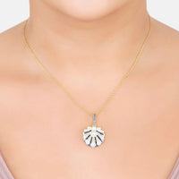 Gold necklace on model with small blue scallop-shell pendant and pearl center
