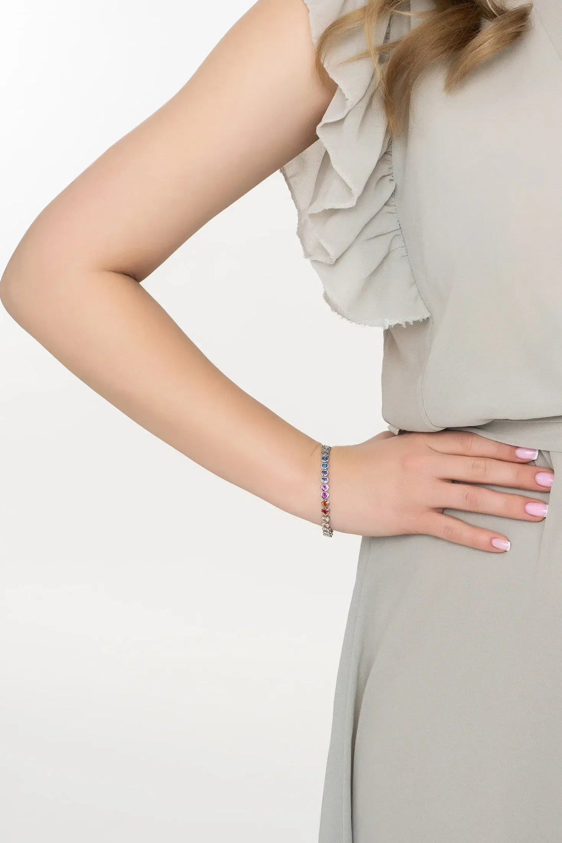 Heart tennis bracelet on wrist with multicolored stone charms and silver chain