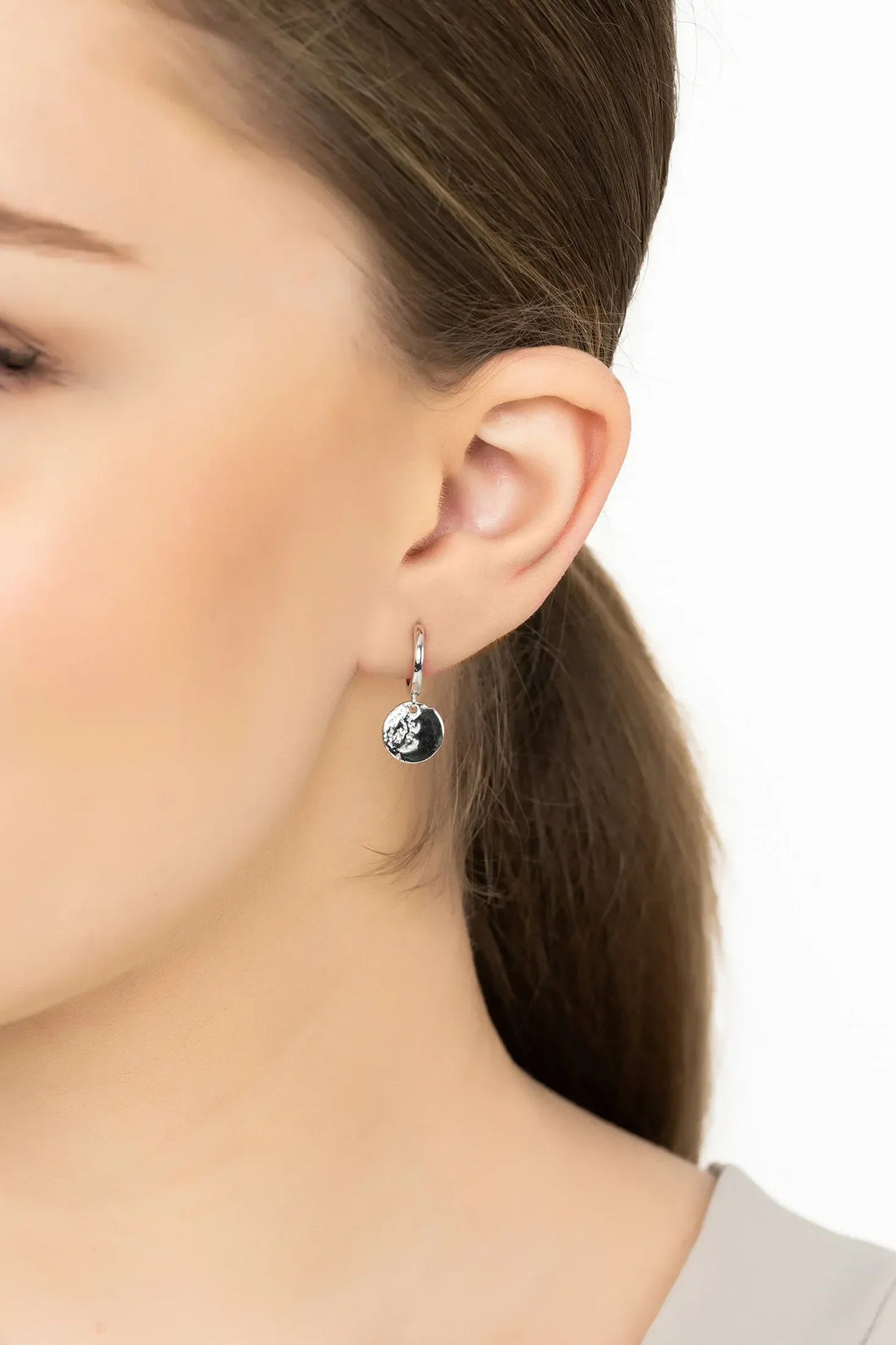 Moon huggie hoop earrings with round moon charm on silver hook, worn