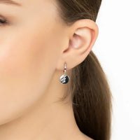 Moon huggie hoop earrings with round moon charm on silver hook, worn
