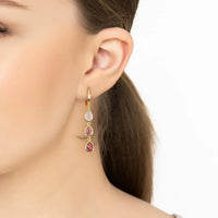 Gold triple teardrop drop earrings with pink stones on model ear