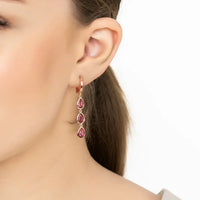 Close-up of rose gold triple teardrop earrings with pink stones on ear