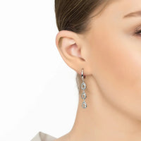 Silver triple teardrop earrings with blue topaz stones on ear