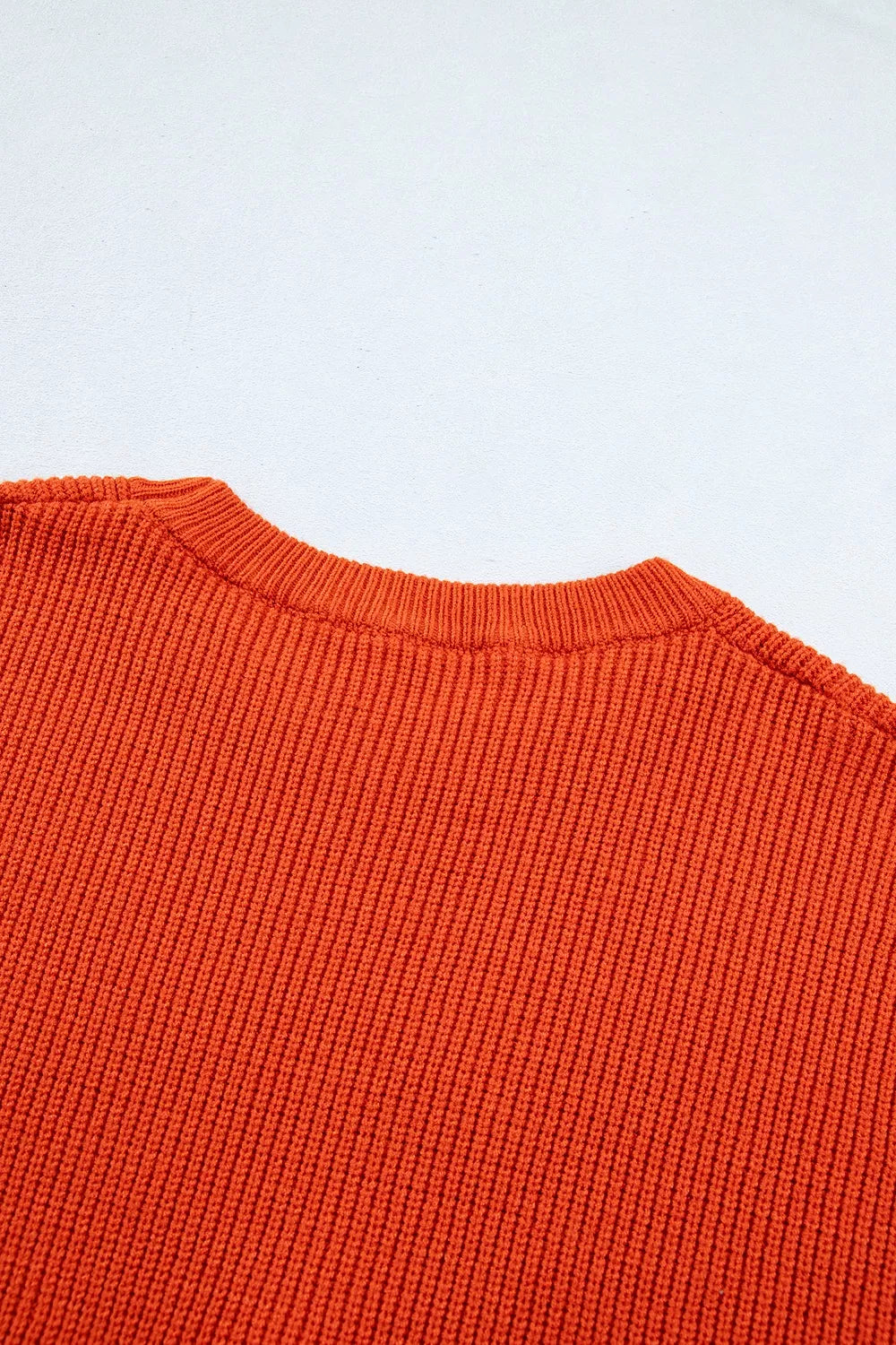 Orange knit sweater with ribbed crew neck and textured stitch pattern, long sleeves