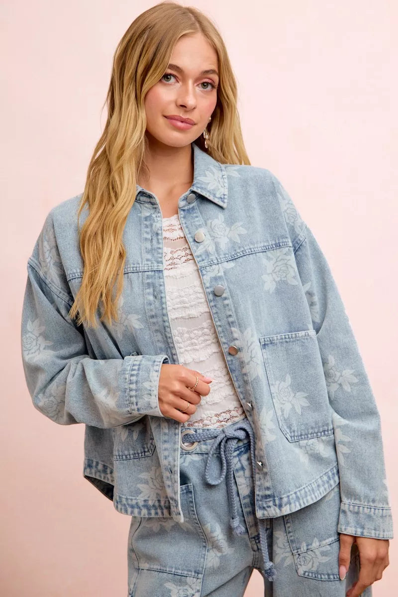 Light blue washed denim jacket with white floral print, button front, and front pockets