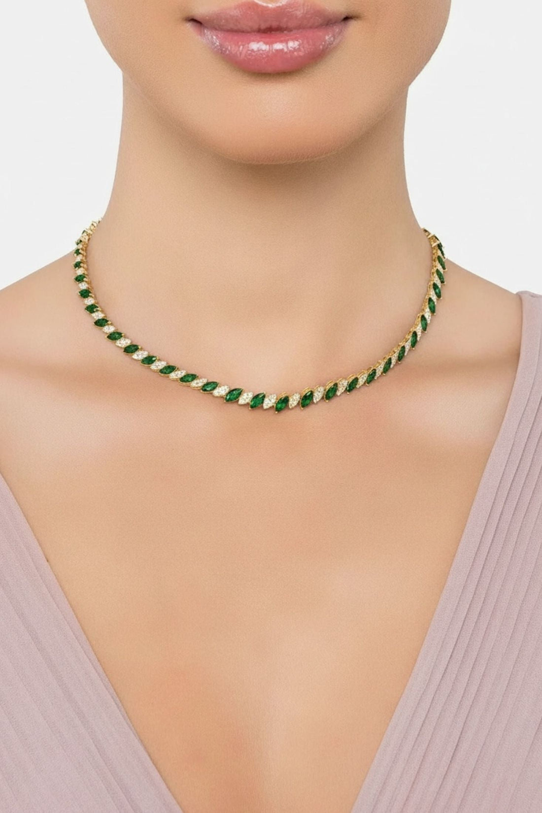 Emerald-green and gold-tone tennis necklace on model neckline, teardrop stones row