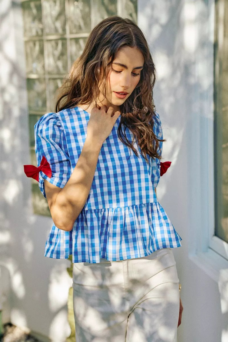 Blue gingham short-sleeve peplum blouse with red bow ties and gathered waist detail