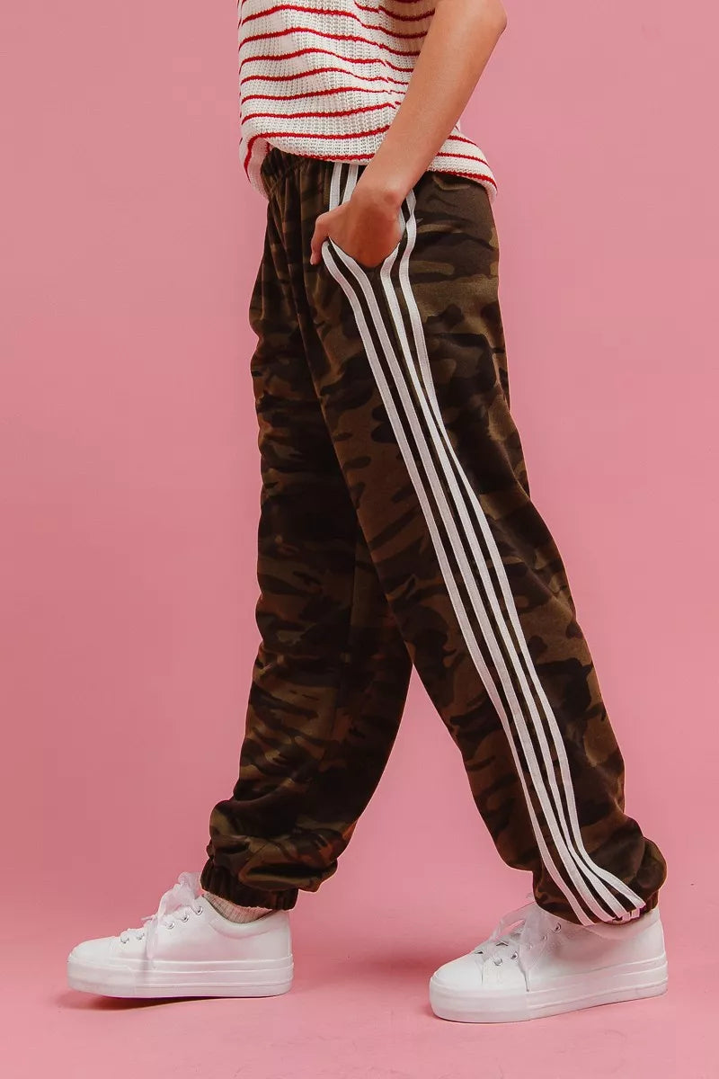 Camouflage track pants with white side stripe detail and relaxed tapered leg.