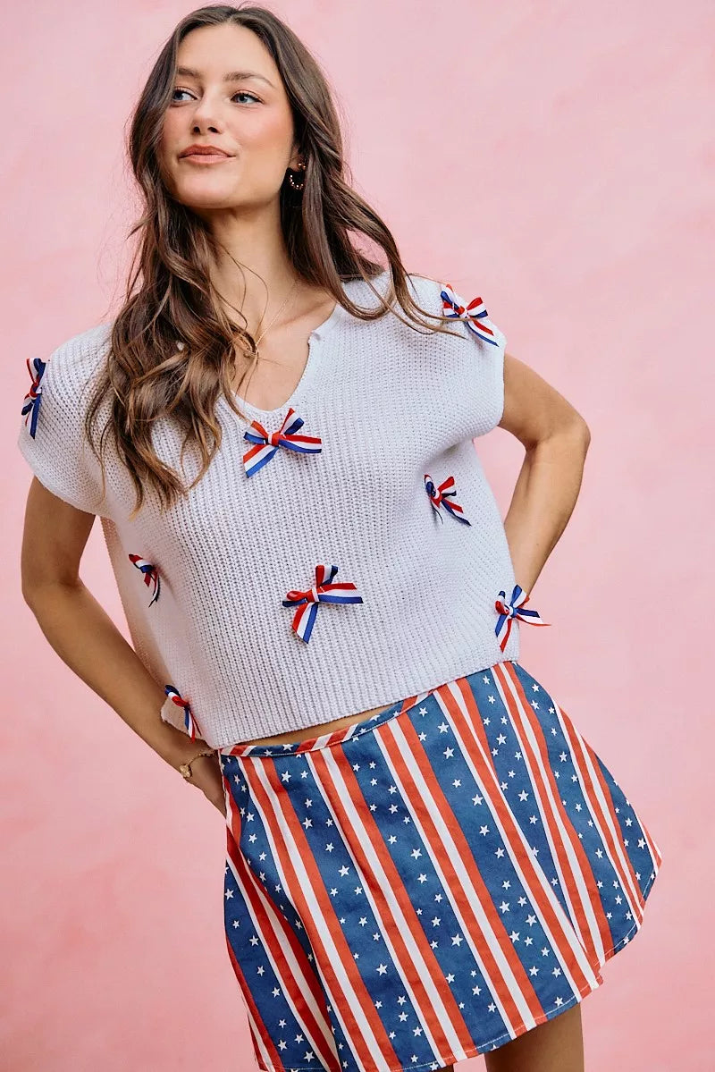Off-white dolman sweater top with scoop neckline and ribbon bow trim