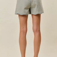 Back view of light-wash denim shorts with scalloped hem