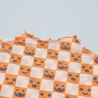 Close-up of orange-and-white checker pattern with jack-o’-lantern faces on lightweight blouse fabric