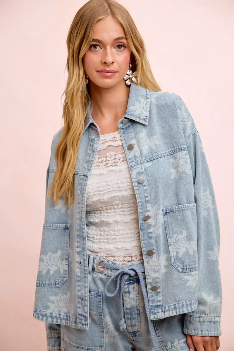 Light blue denim jacket with white floral print and button front, chest pocket detail