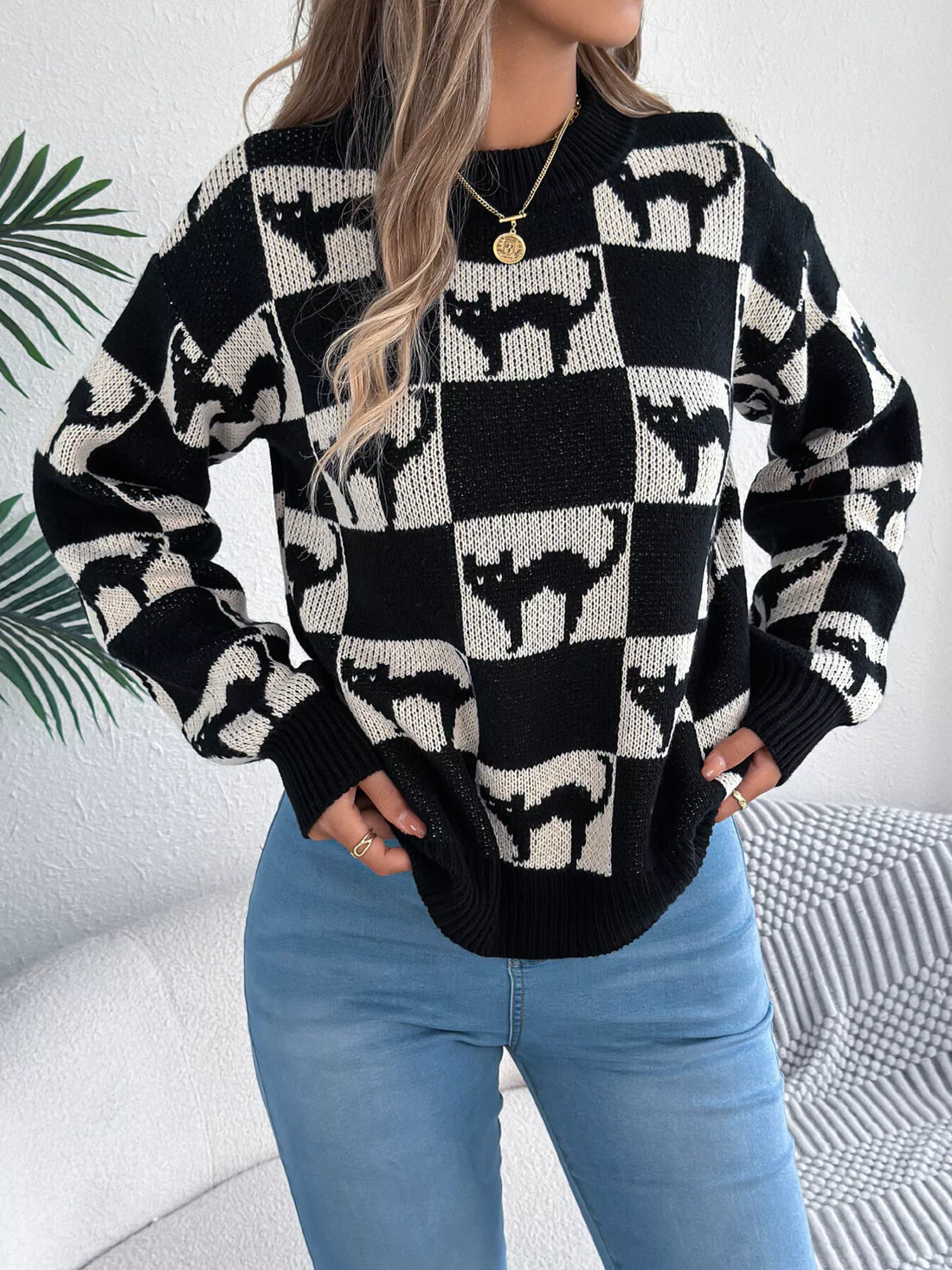Three-quarter view of black and cream ghost checkerboard knit sweater with ribbed cuffs