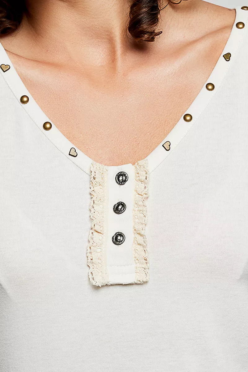 Cream neckline close-up: heart-studded trim and button-front ruffle placket