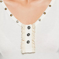 Cream neckline close-up: heart-studded trim and button-front ruffle placket