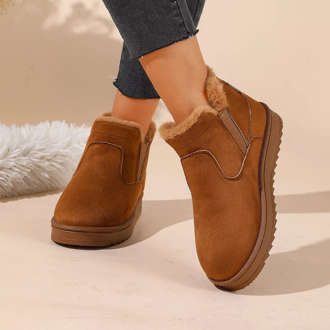Tan suede-look ankle boots with side elastic, faux fur lining, and textured outsole