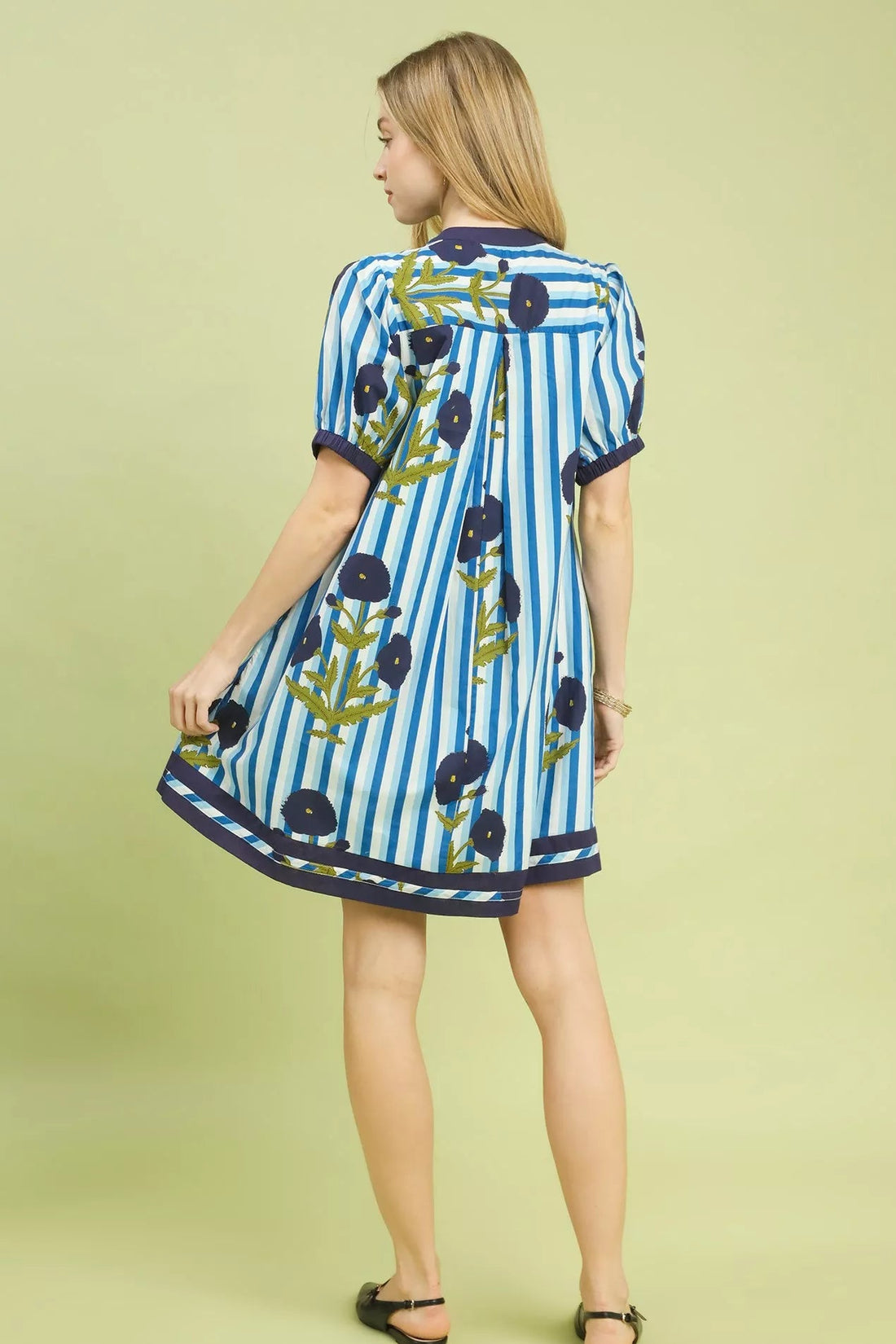 Back view of blue striped short dress with navy trim and floral print