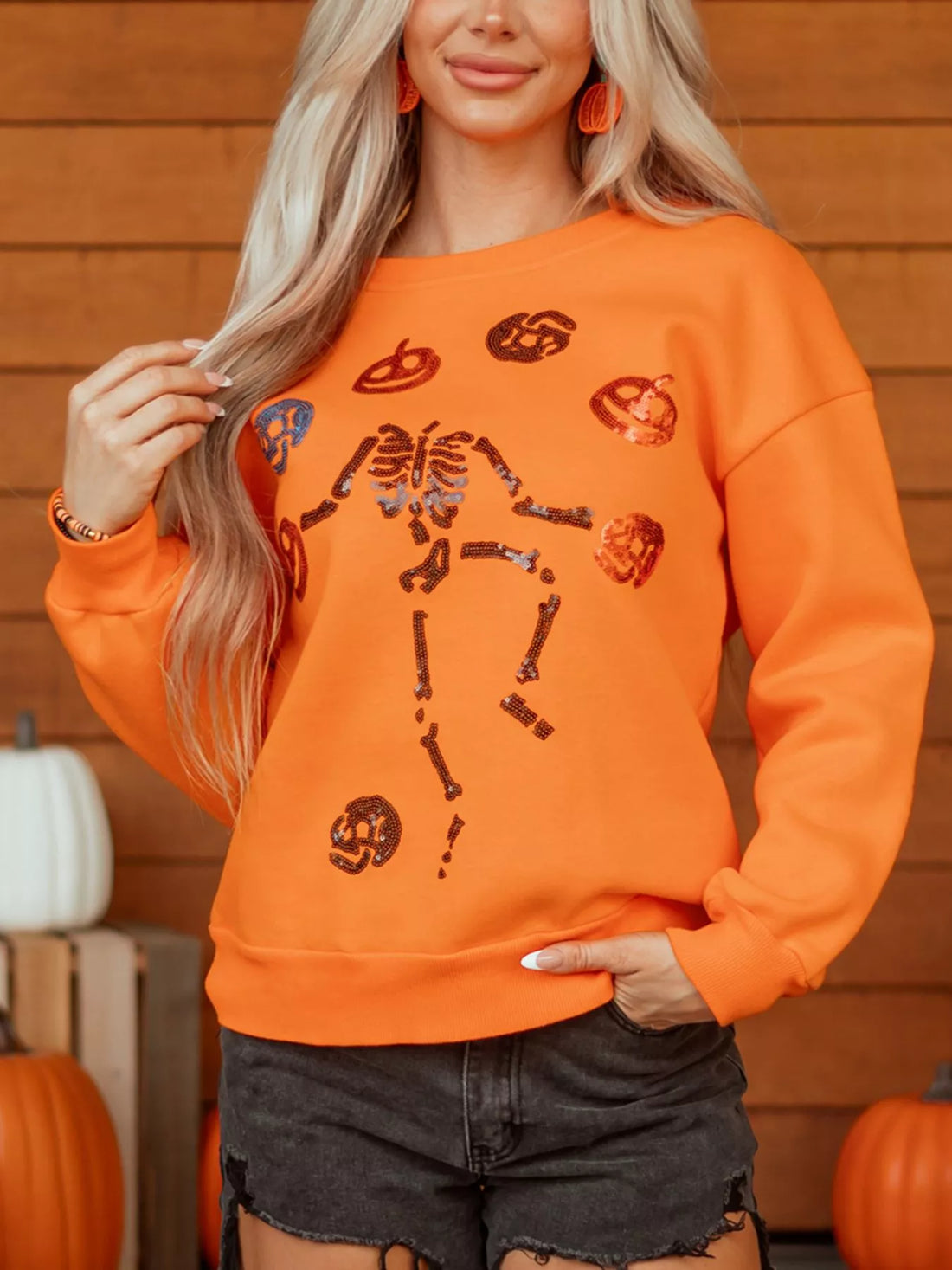 Orange Halloween crewneck sweatshirt with sequin critter icons and skeleton graphic