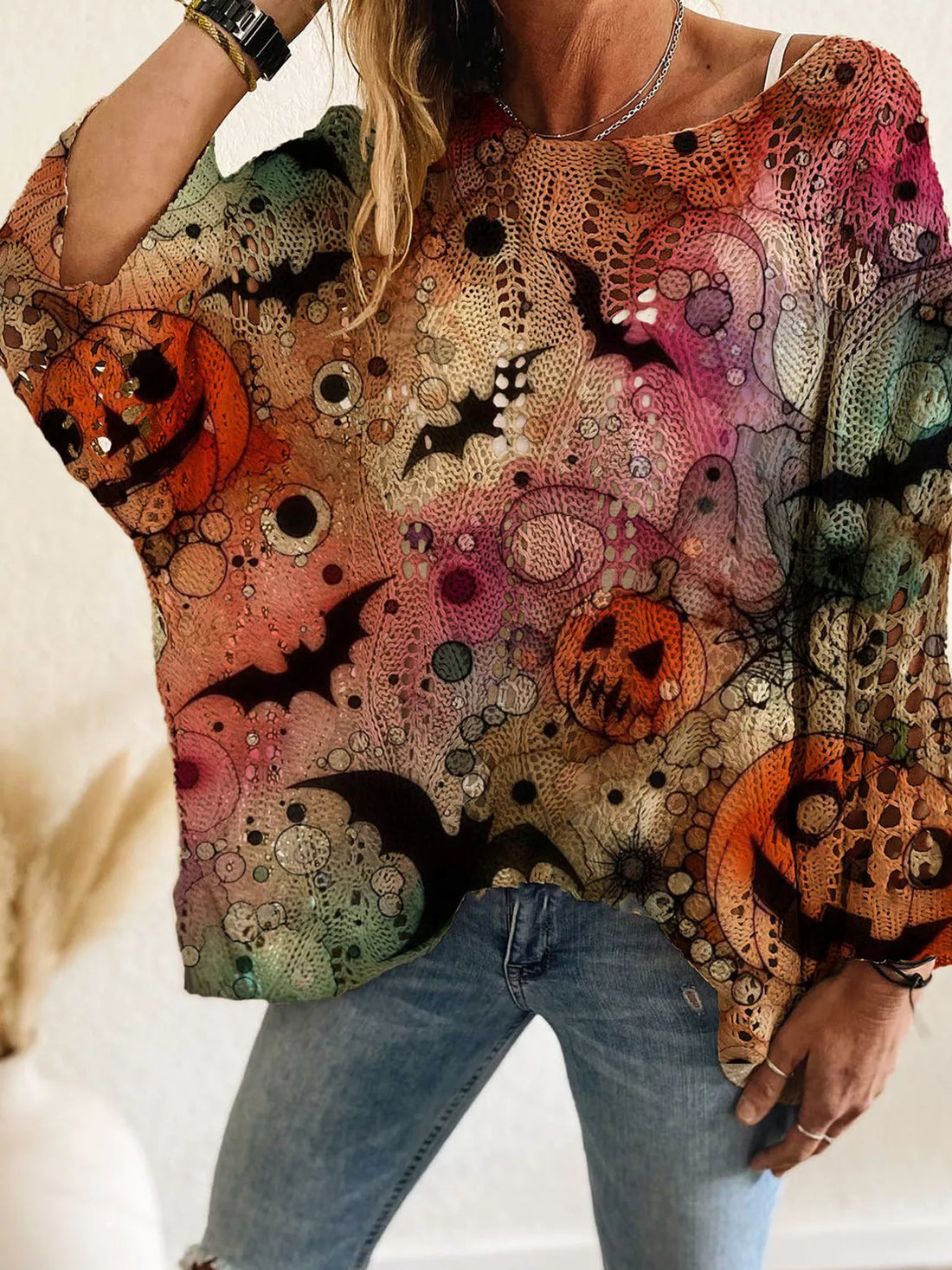 Plus size loose knit cover-up with multicolor Halloween graphics in pink, green, orange, and cream.