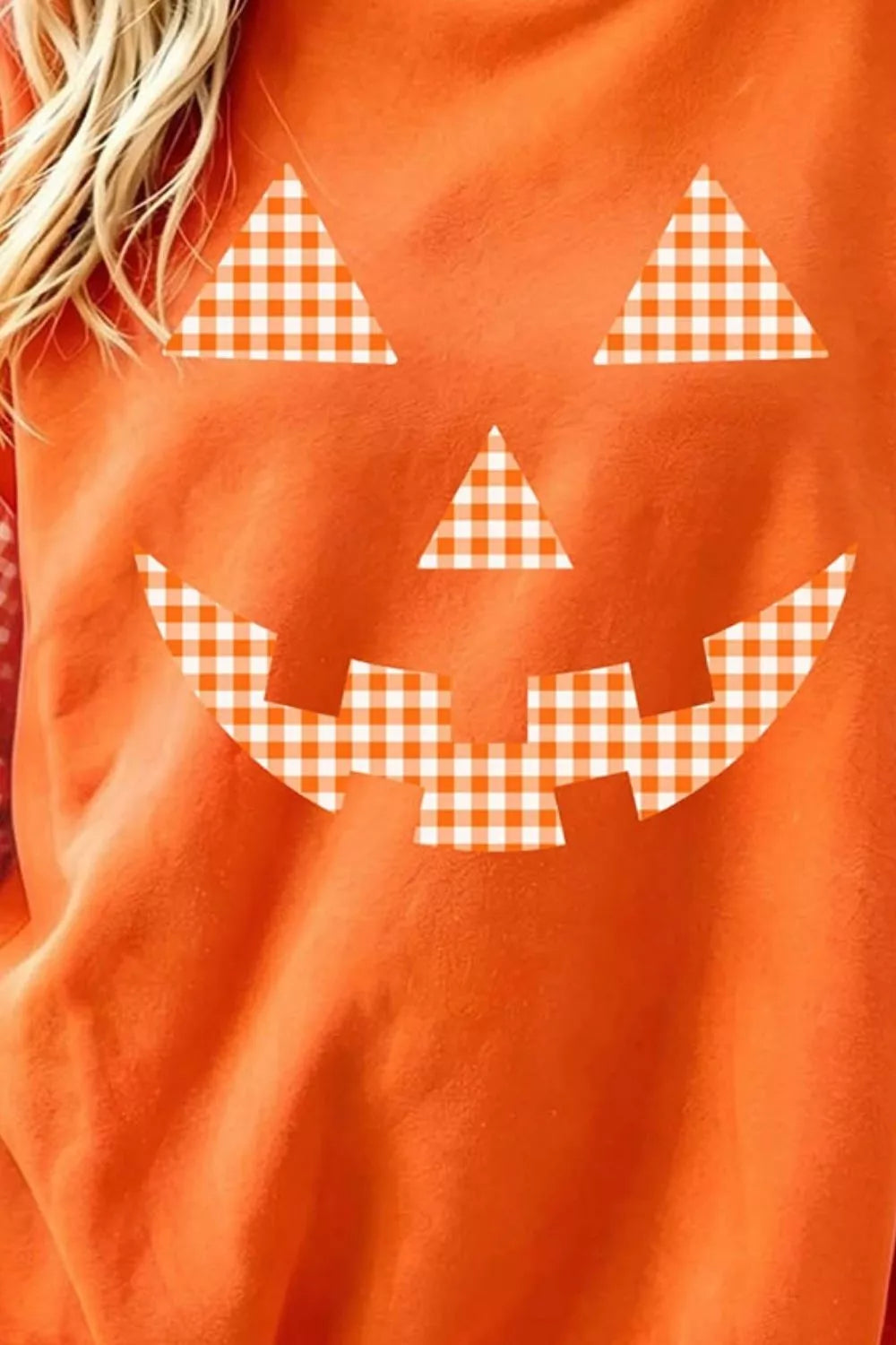 Close-up orange sweatshirt with checkered plaid pumpkin face graphic