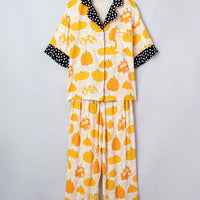 Laid-out pumpkin print pajama set with polka-dot-trim collar and cuffs, button-front top