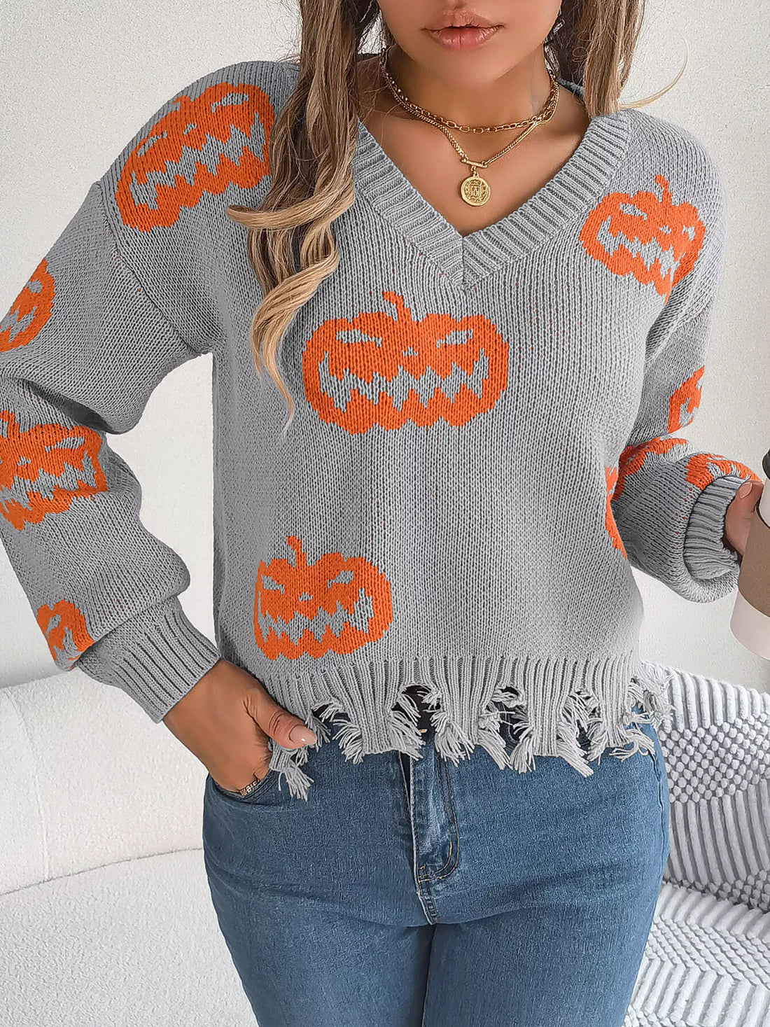 Gray V-neck sweater with orange pumpkin knit and distressed, frayed bottom hem