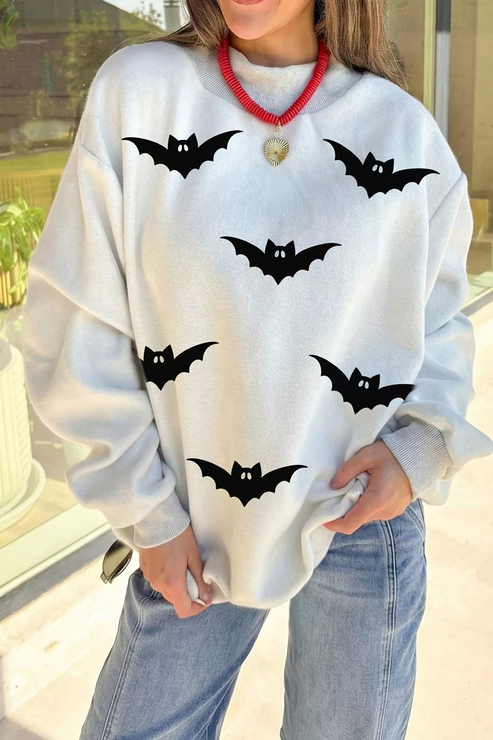 Light gray reversible mock-neck sweatshirt with black bat print and red collar trim