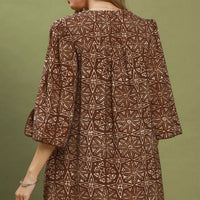 Brown geometric print tunic dress, back view with flared sleeves and patterned hem